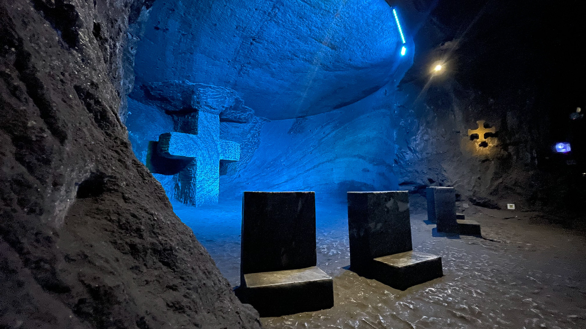 Podzemna Katedrala soli v Zipaquiráju v Kolumbiji, z velikim križem, modro osvetljenimi stenami in kamnitimi klopmi.